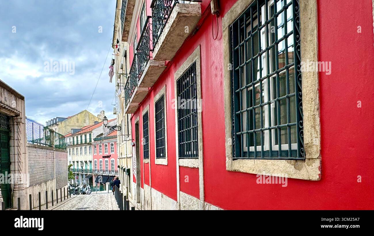 Residential dwelling with bright red exterior walls and barred windows for security in Lisbon Portugal - Smartphone Captured Stock Image