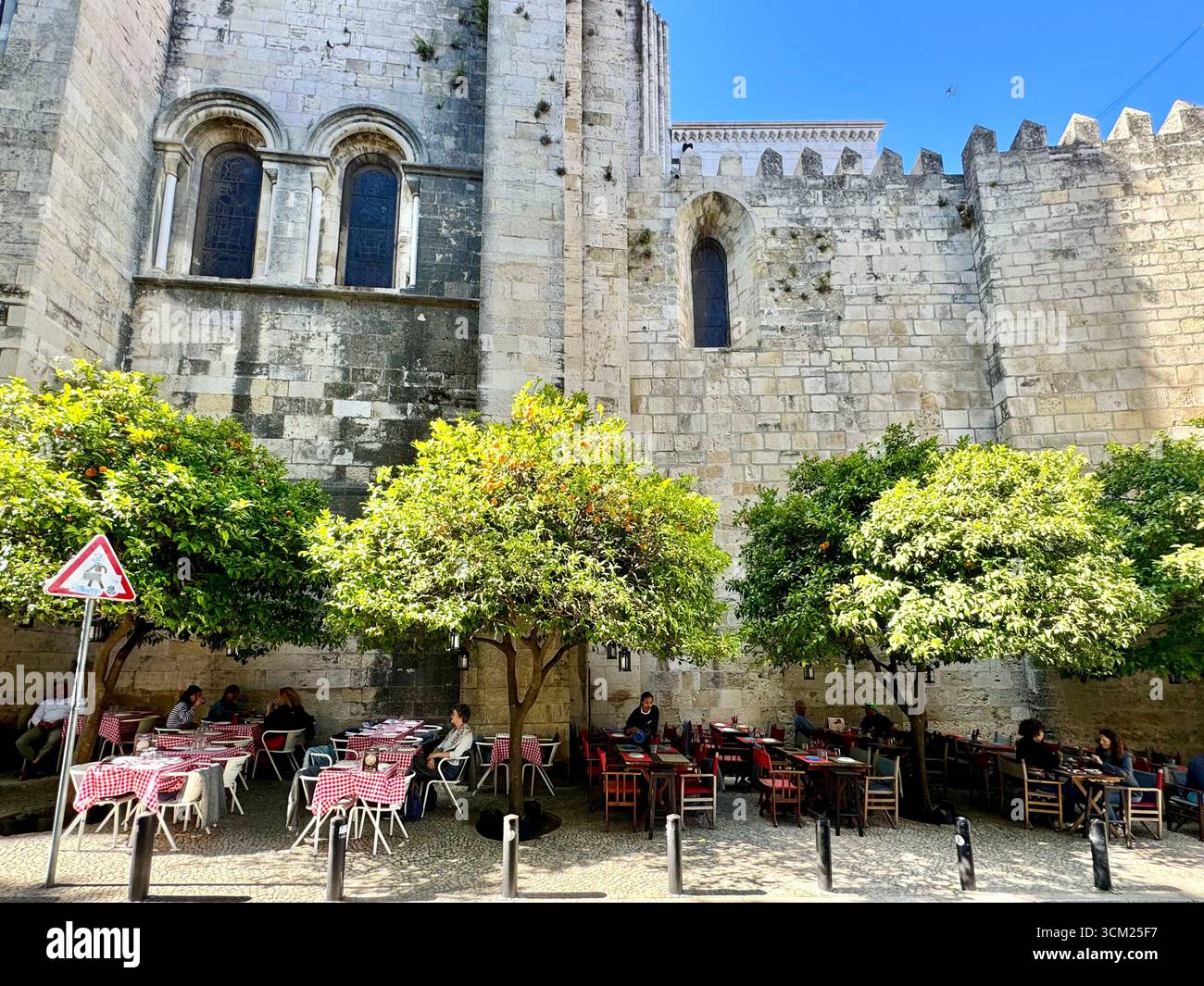 Al fresco dining at a restaurant along side exterior wall of Lisbon Cathedral in Alfama Lisbon Portugal - Smartphone Captured Stock Image