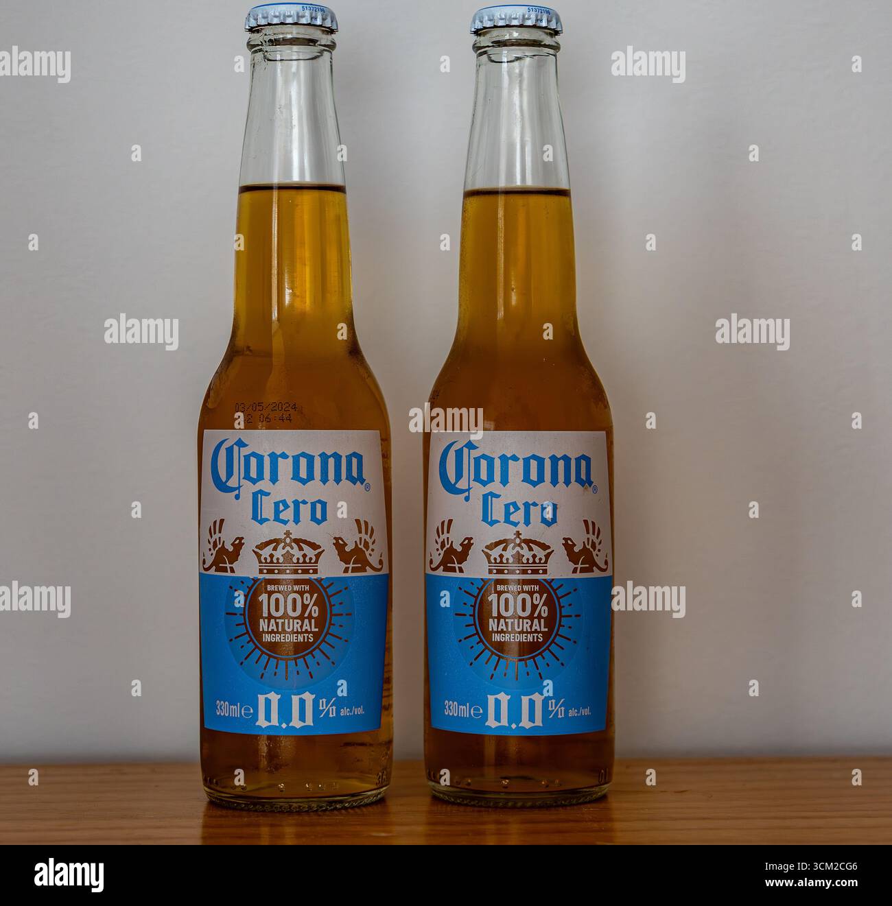 Two bottles of Corona Cero non-alcoholic beer on a wooden surface against a plain white background Stock Photo