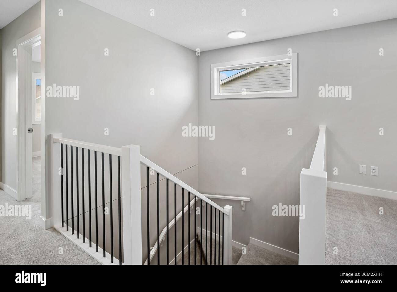 White staircase with a black railing leading to a window. The window is ...