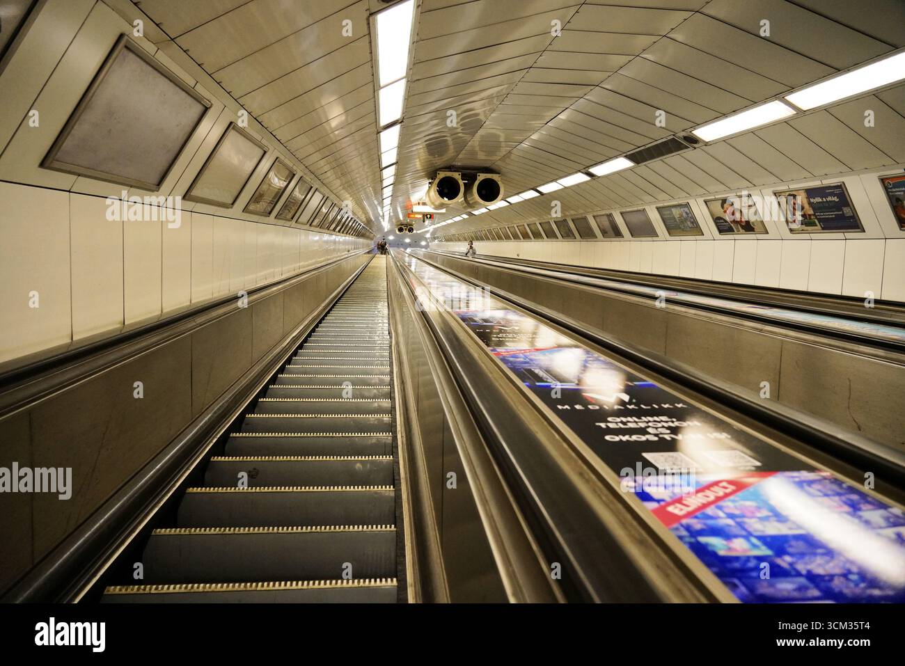 Escalator metro station, Budapest, Hungary, Europe, Empty escalator in a futuristic metro shaft with symmetrical lighting Stock Photo