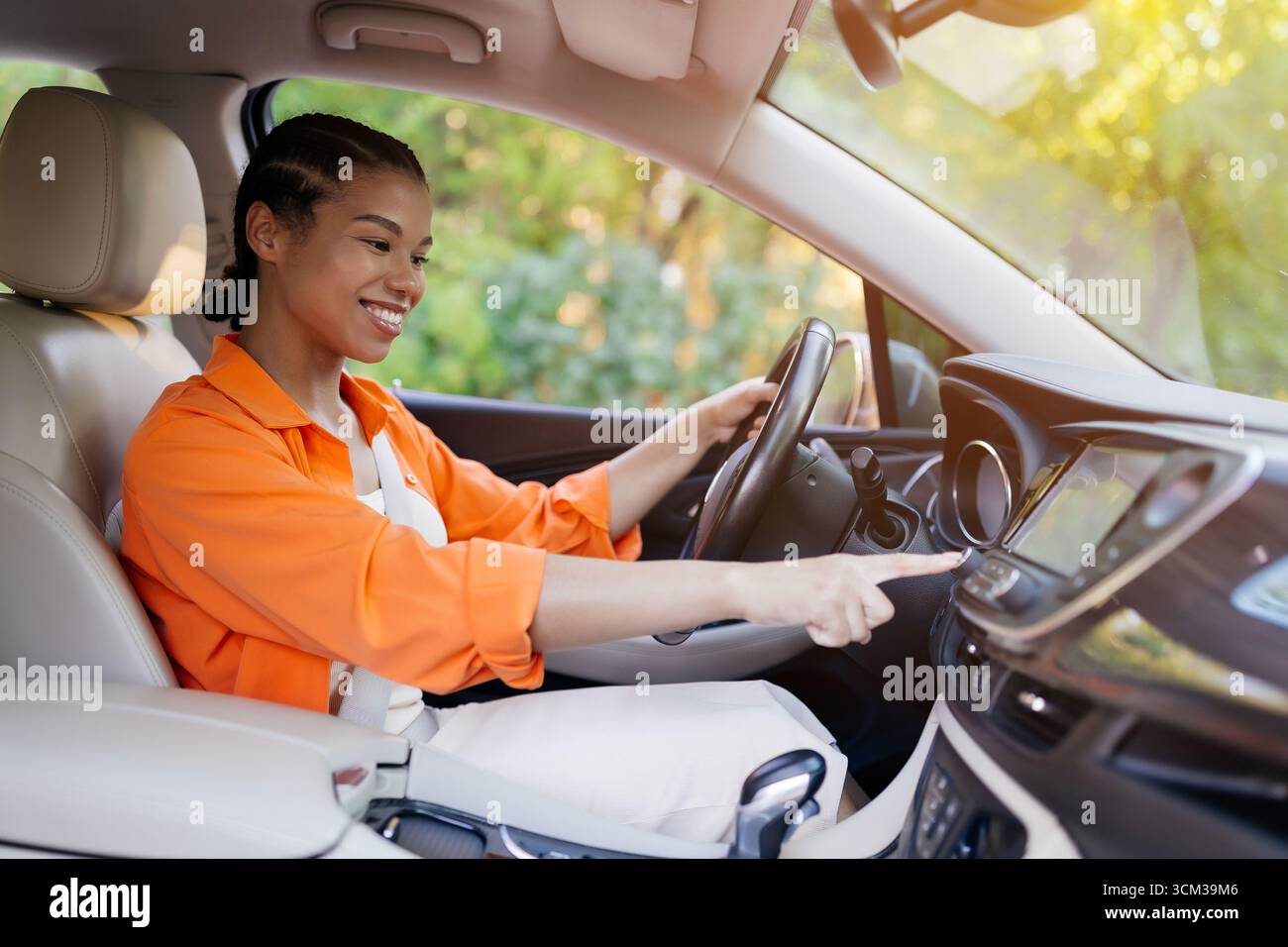 Smiling African American woman in car using touchscreen display, adjusting navigation Stock Photo