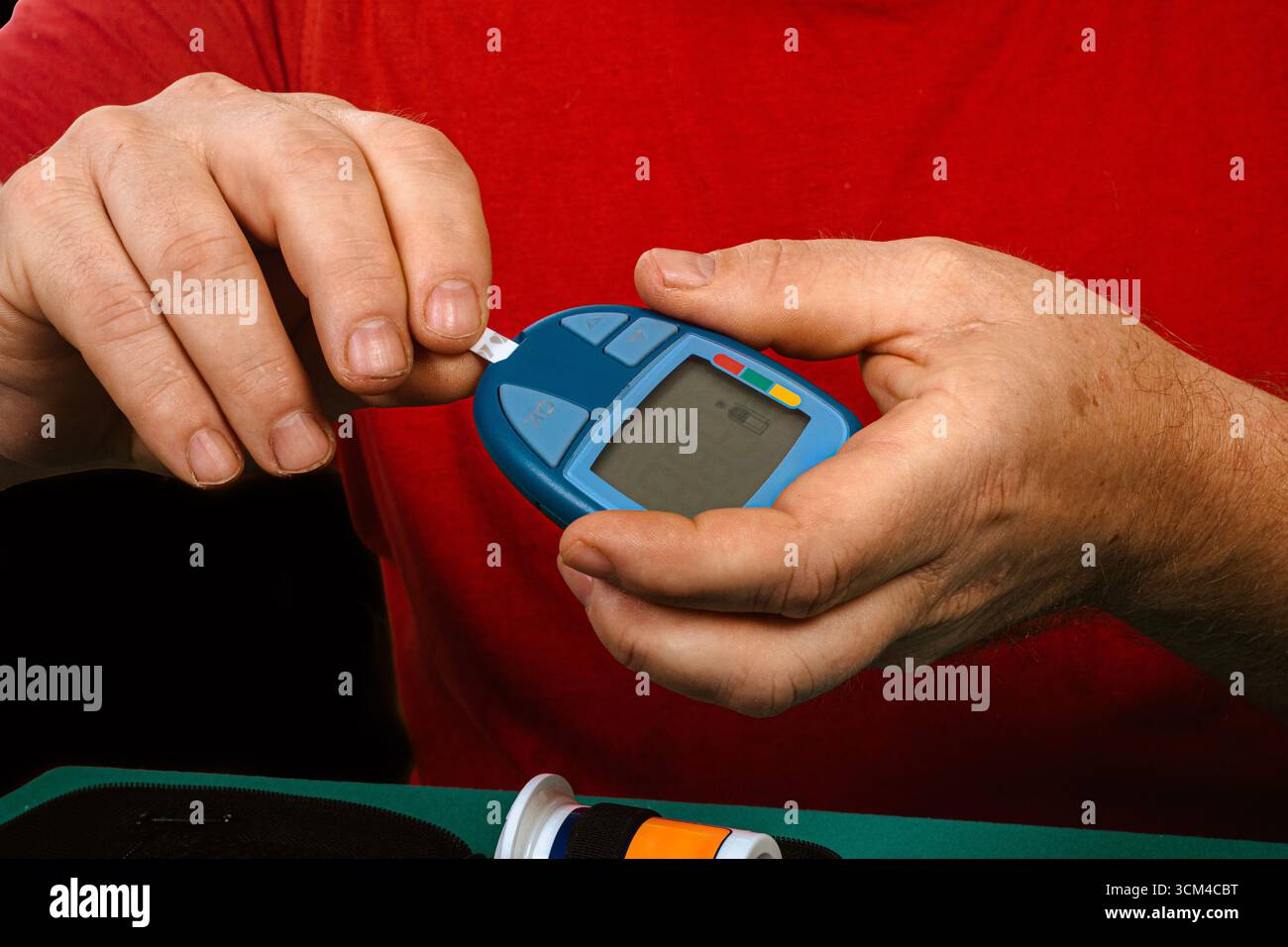 Close up of a person using a glucose meter to monitor blood sugar levels, highlighting the importance of diabetes management and healthcare Stock Photo