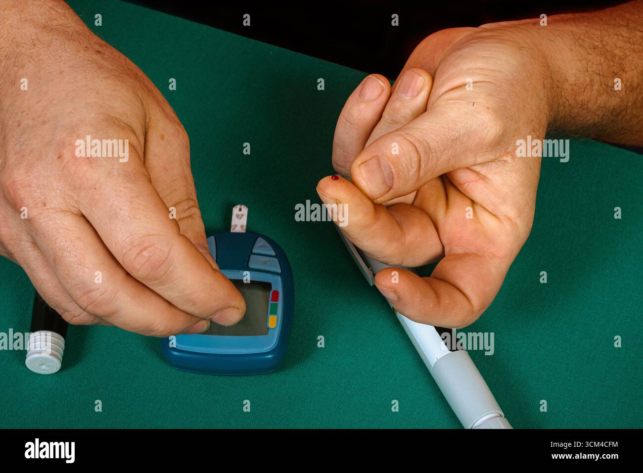 Close up of a man using a portable glucometer to measure his blood sugar levels, highlighting the importance of diabetes management and healthcare Stock Photo