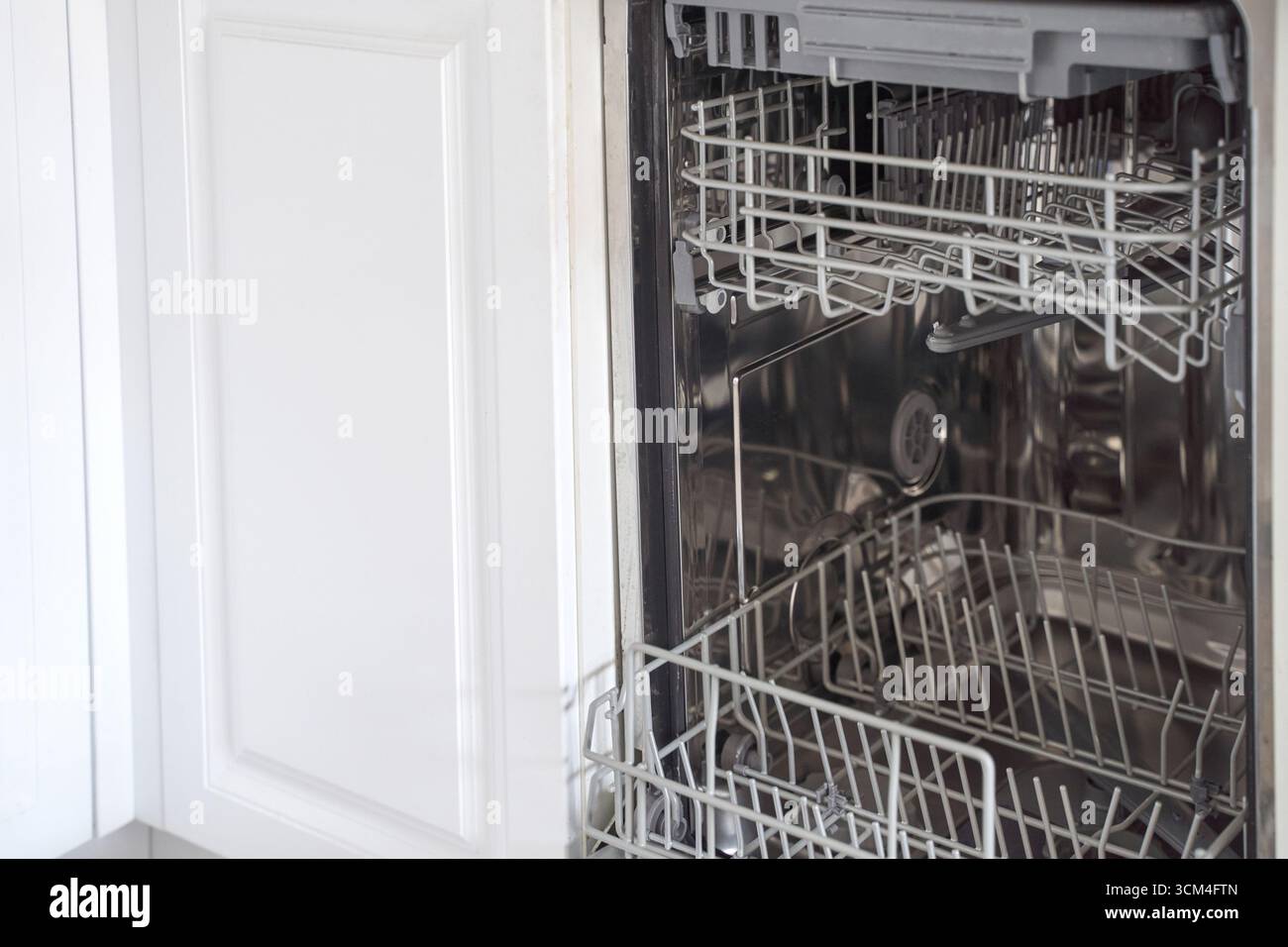 Open dishwasher with empty racks in a modern kitchen interior showing ...