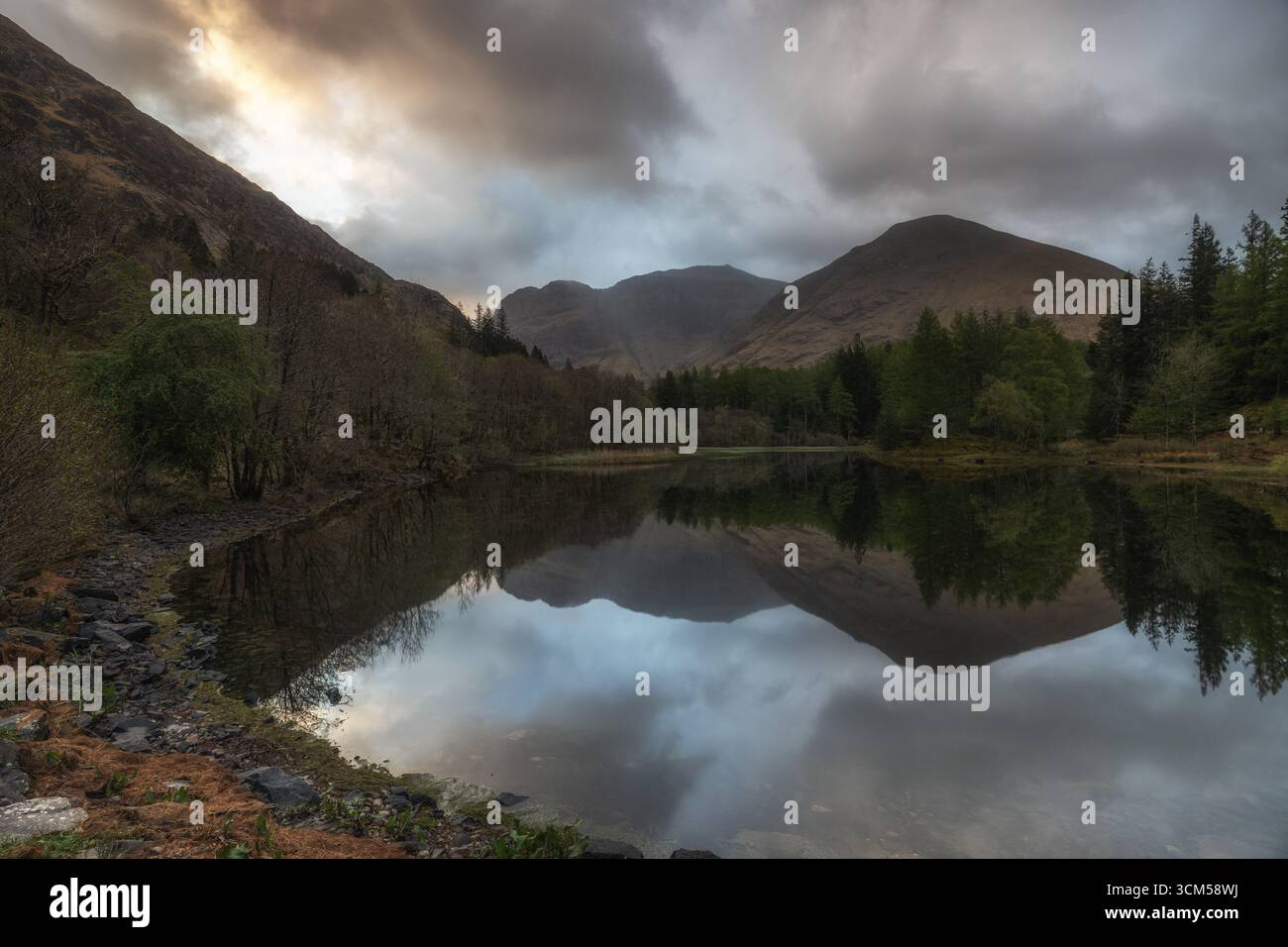 Mountains and sky are reflected in a small lake in the Scottish Highlands, Glencoe. Stock Photo