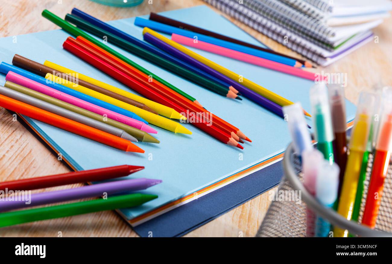 Multicolored pencils on table with papers and notebooks Stock Photo