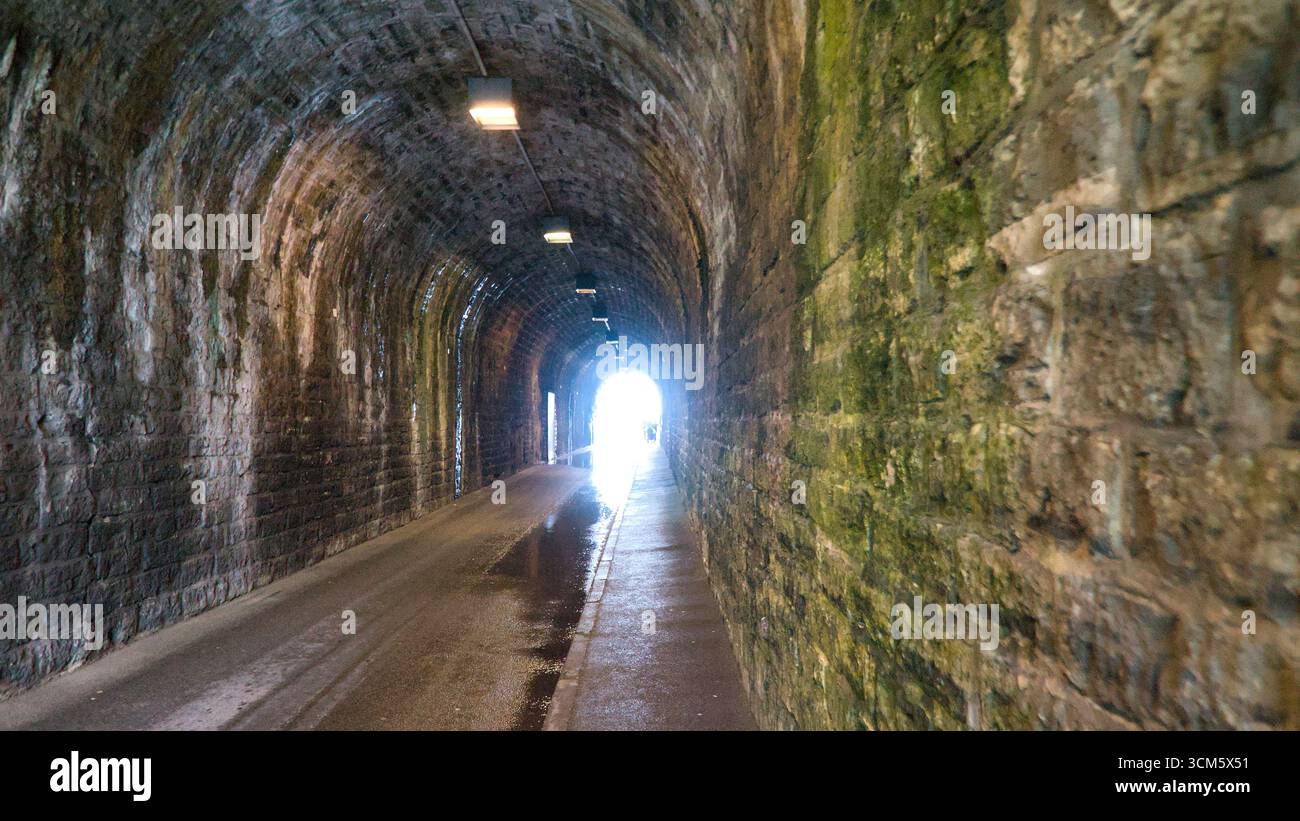 View inside a narrow tunnel with light at the end, concept of hope and perspective. Stock Photo
