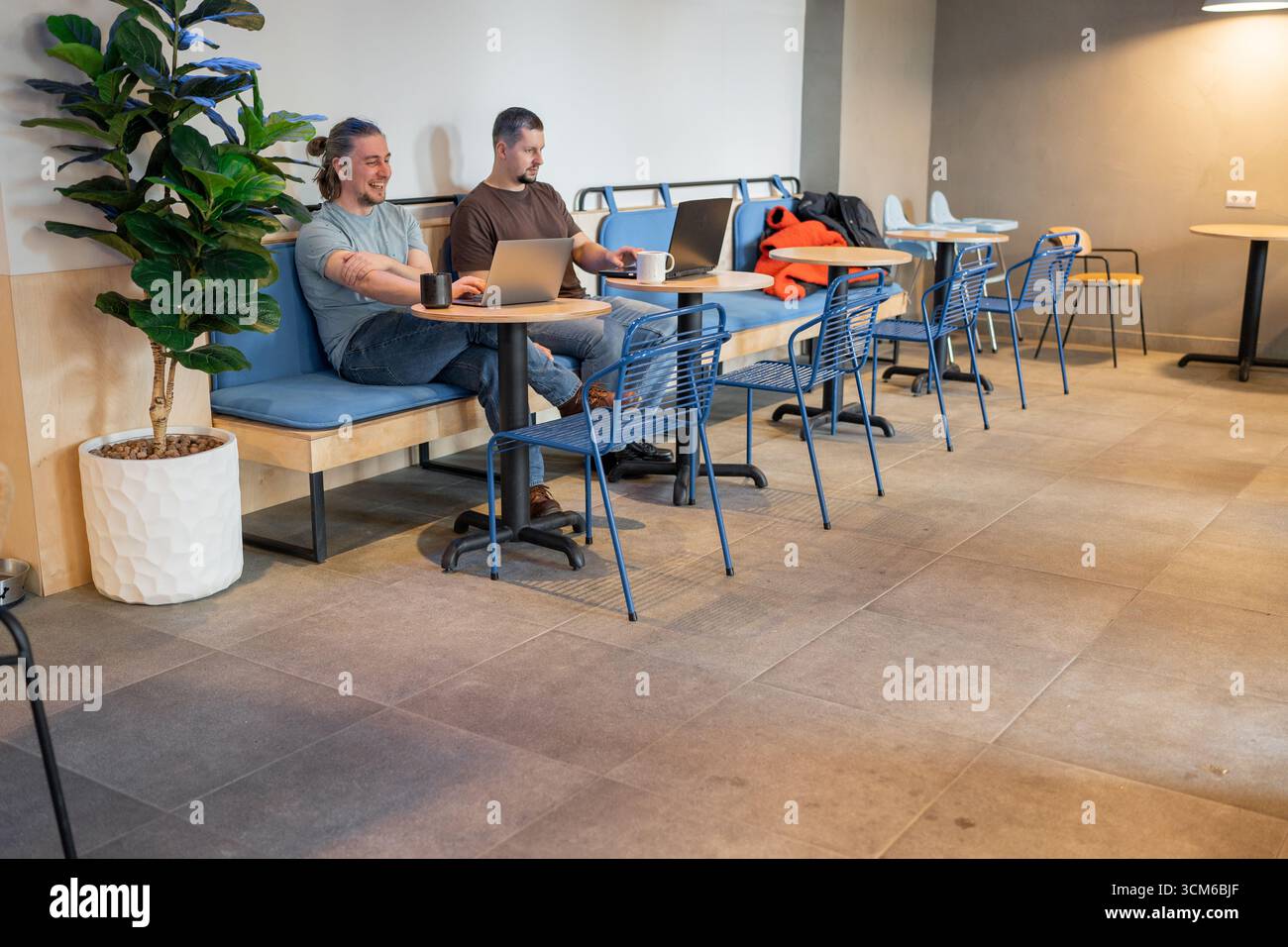 Two laughing It Software engineers working on project and programming in coffee shop. Successful start up project concept. Stock Photo