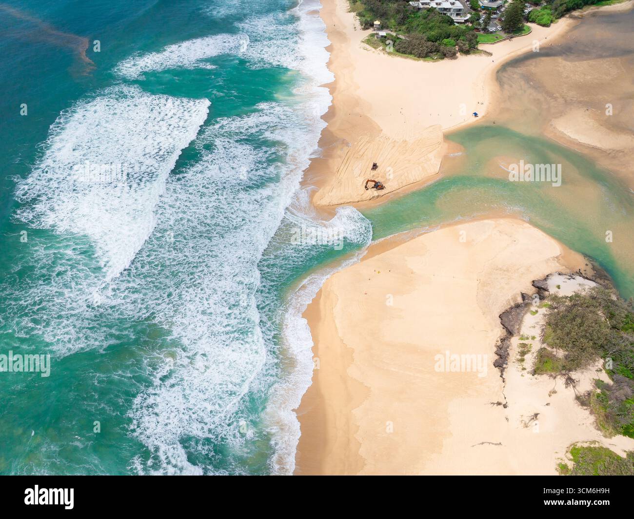Aerial view of water from a lake flowing over a sandy beach into waves ...