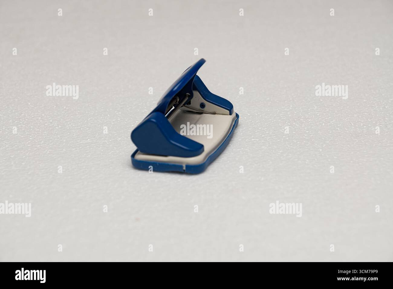 A blue stapler on a white textured surface Stock Photo