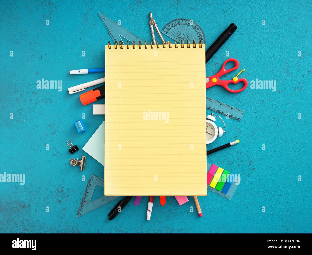 School supplies framing a blank notepad on a blue background, creating a vibrant back to school concept Stock Photo