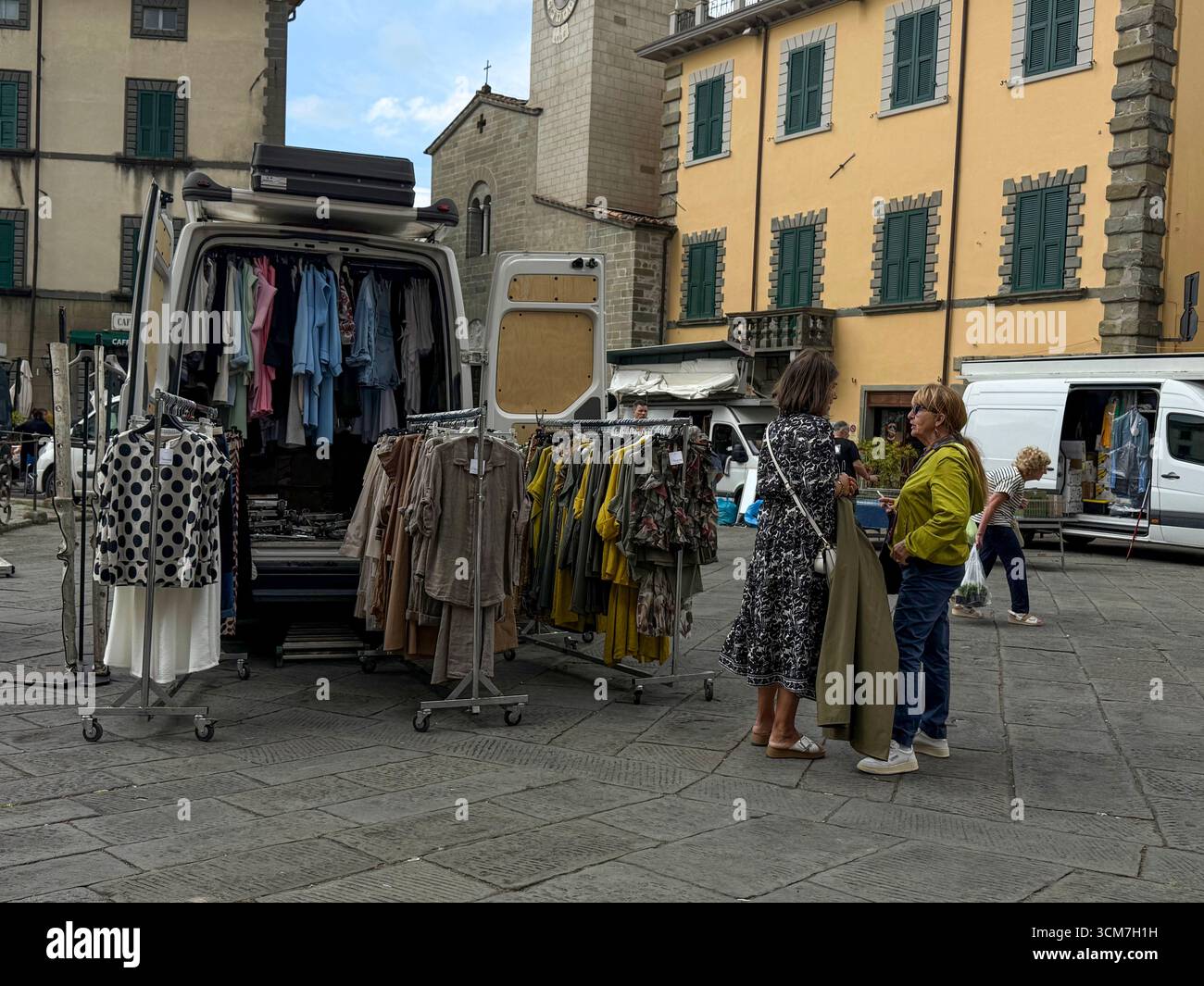 A Ladies fashion stall with a van  at the weekly market held in front of the Chiesa del S. Jacopo e Antonio (Church of S. and Antonio on the 16th cent - Smartphone Captured Stock Image