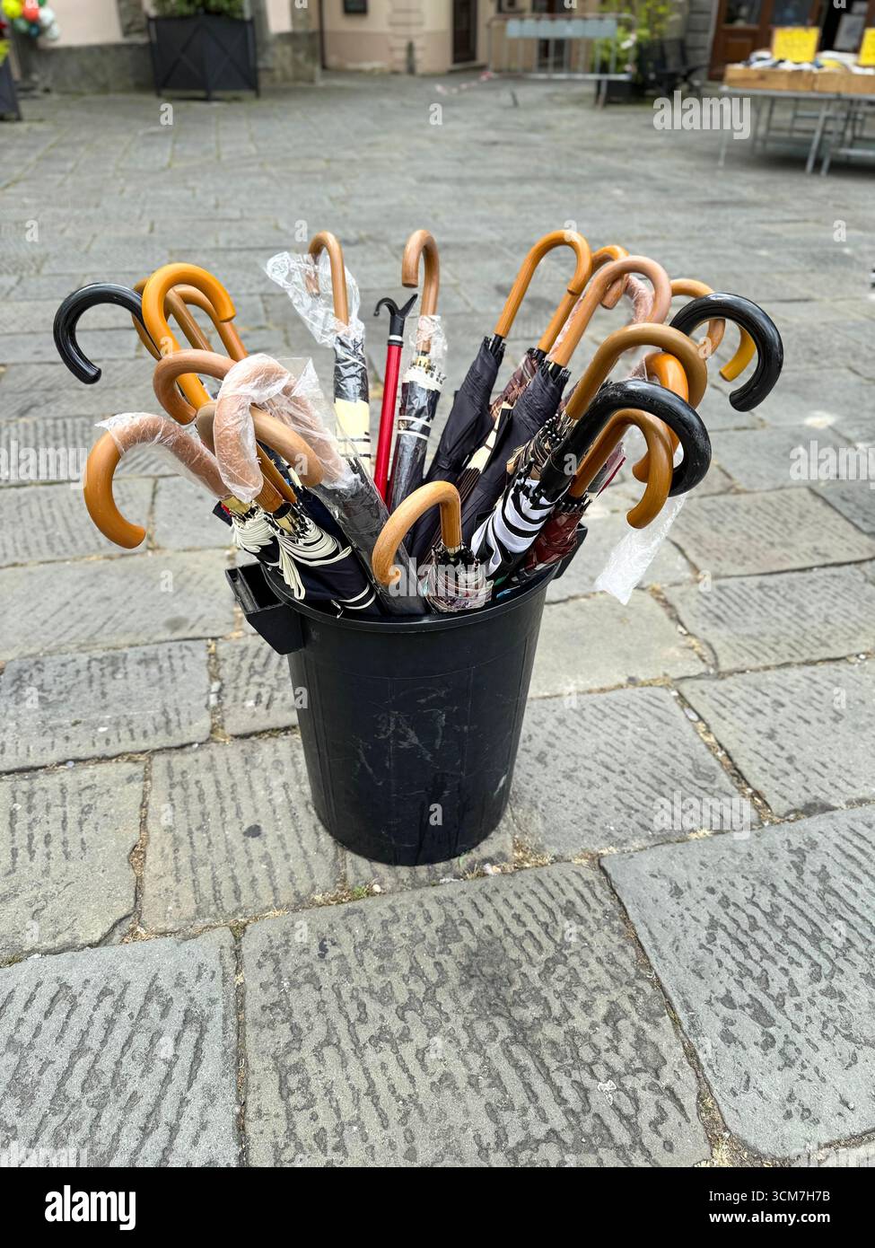 A rack of umbrellas on sale at the weekly market held on the 16th century Piazza Medice) in the medieval town of Fivizzano, a commune in the province - Smartphone Captured Stock Image