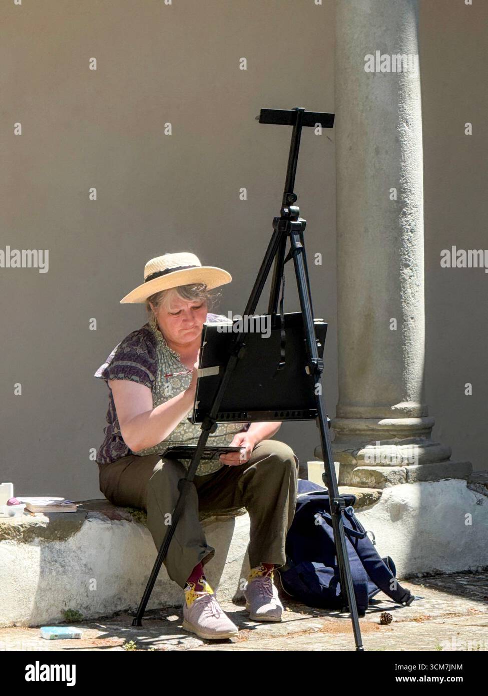 An artist in the courtyard with surrounding cloisters and a well in the centre at the !6th century monastery called 11 convento del Carmine is near th - Smartphone Captured Stock Image