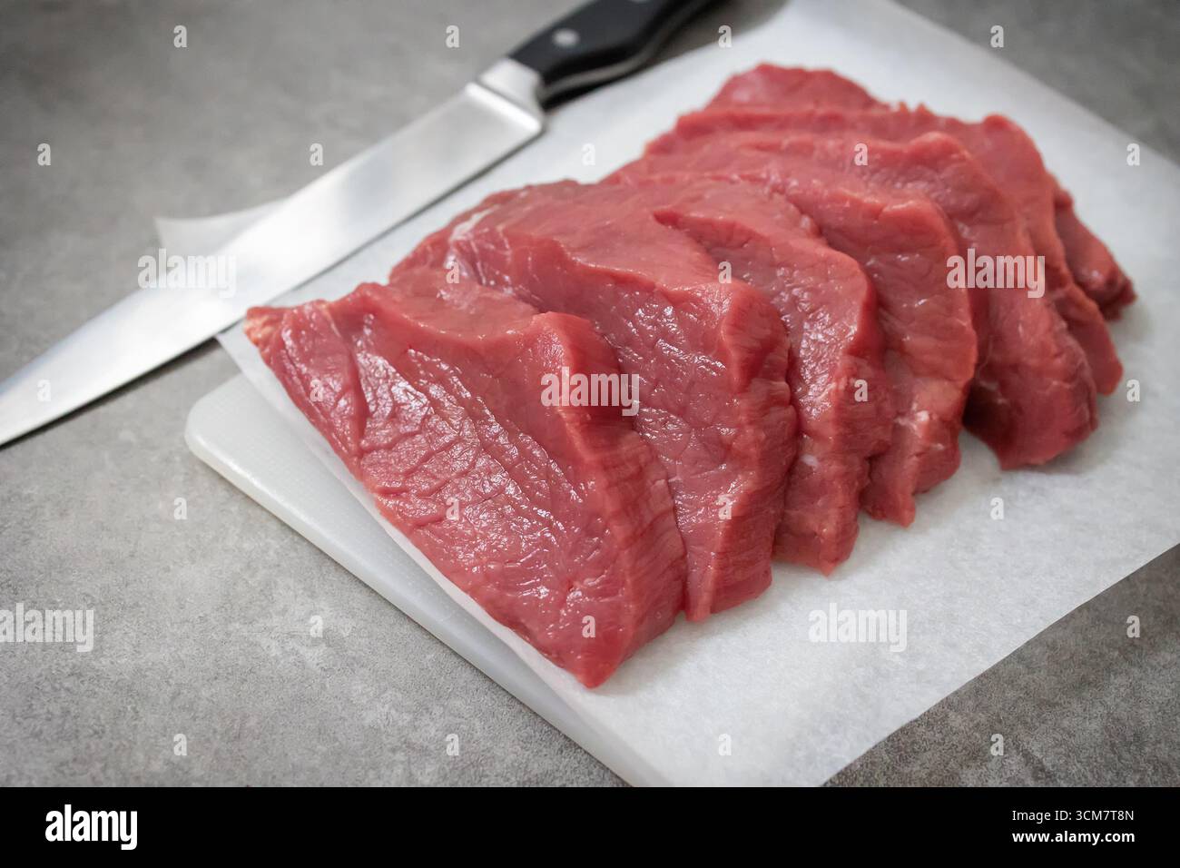 fresh raw sliced beef meat on grey kitchen table Stock Photo