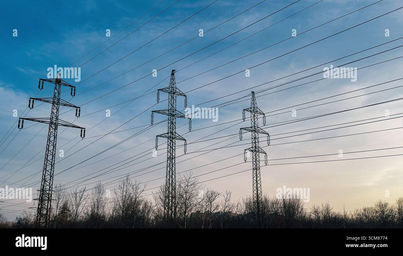 Electric power transmission towers and cables silhouetted against a ...