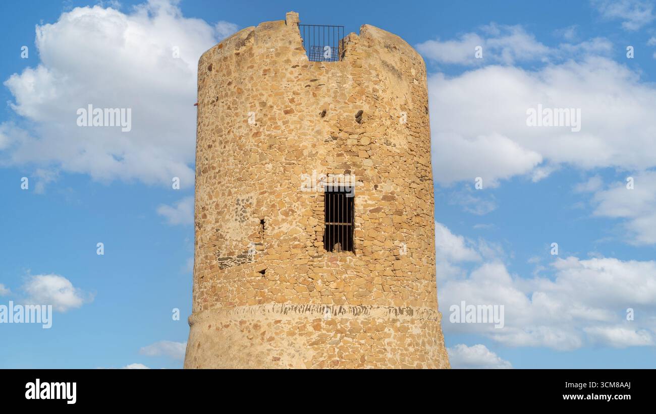 Historic stone watchtower by the sea under blue sky and white clouds ...