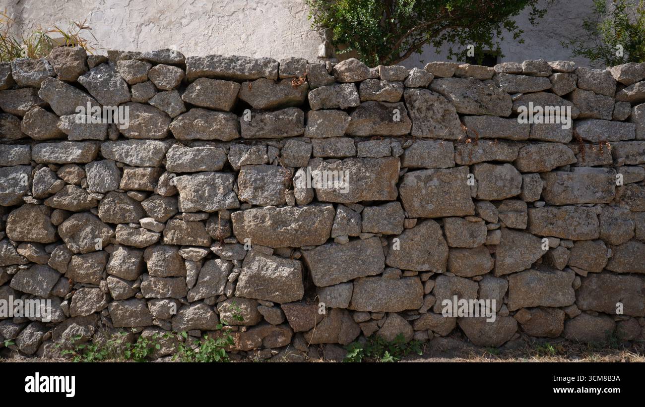 Rustic stone wall with multicolored natural rocks and mortar Stock Photo