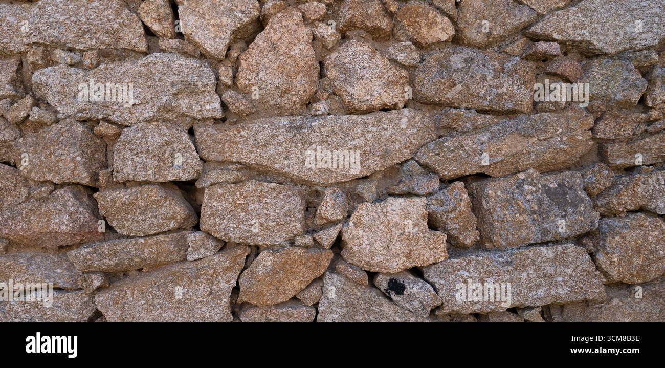 Rustic stone wall with multicolored natural rocks and mortar Stock Photo