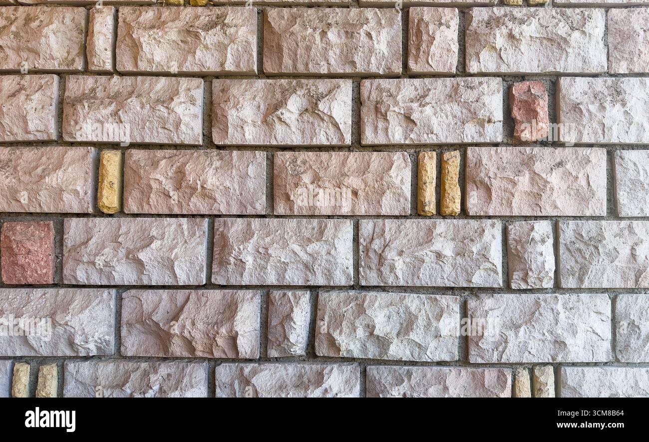 Rustic stone wall with multicolored natural rocks and mortar Stock Photo