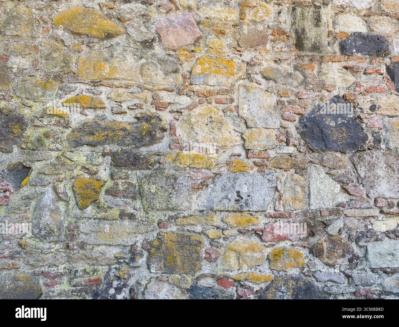 Rustic stone wall with multicolored natural rocks and mortar Stock Photo