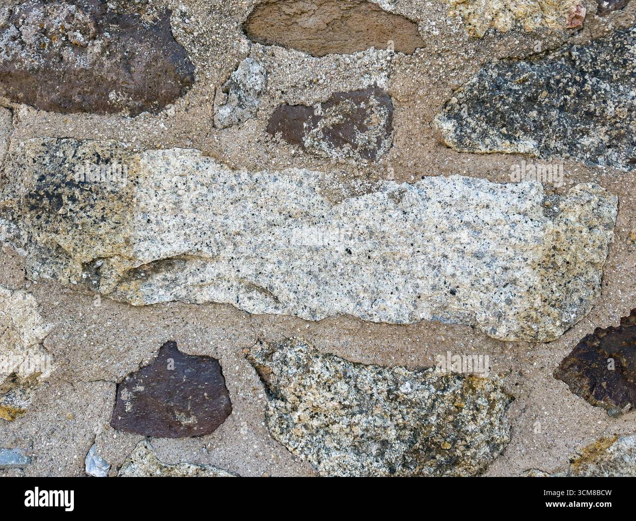 Rustic stone wall with multicolored natural rocks and mortar Stock Photo