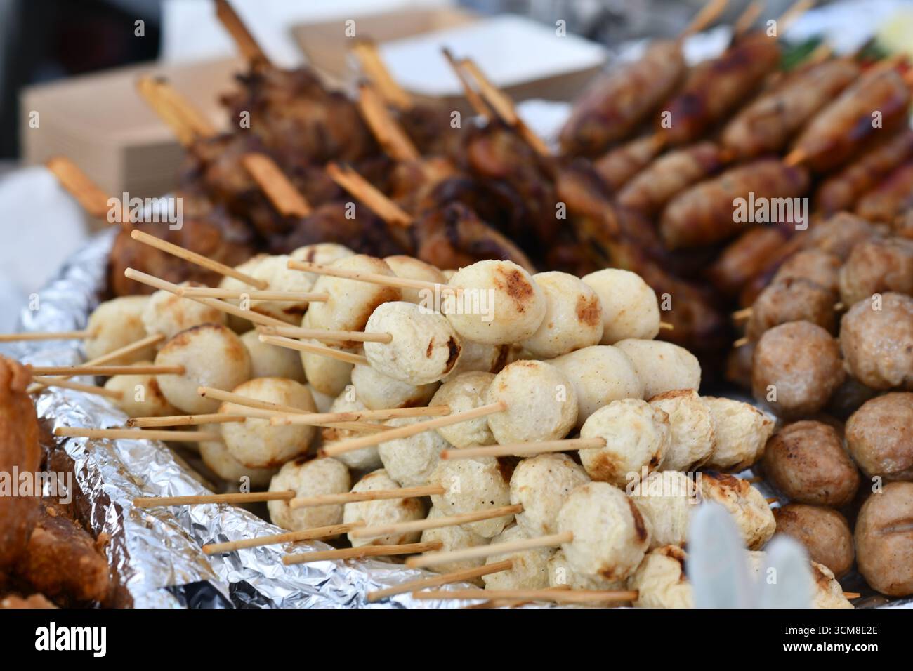 Close up of white Thai fish or chicken meat balls grilled skewers at street food market Stock Photo