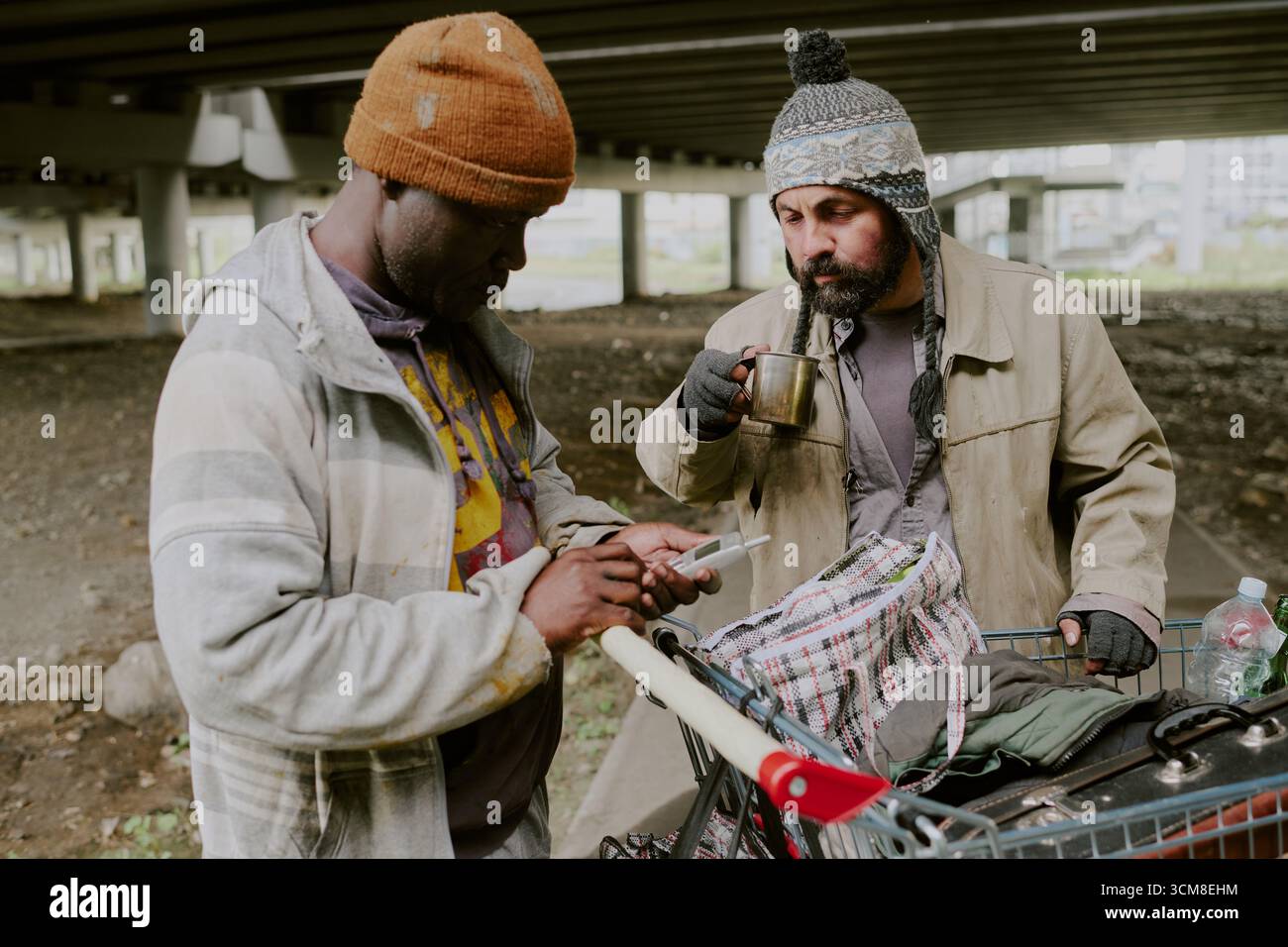 Homeless Men Using Old Phone Standing under Bridge Stock Photo - Alamy