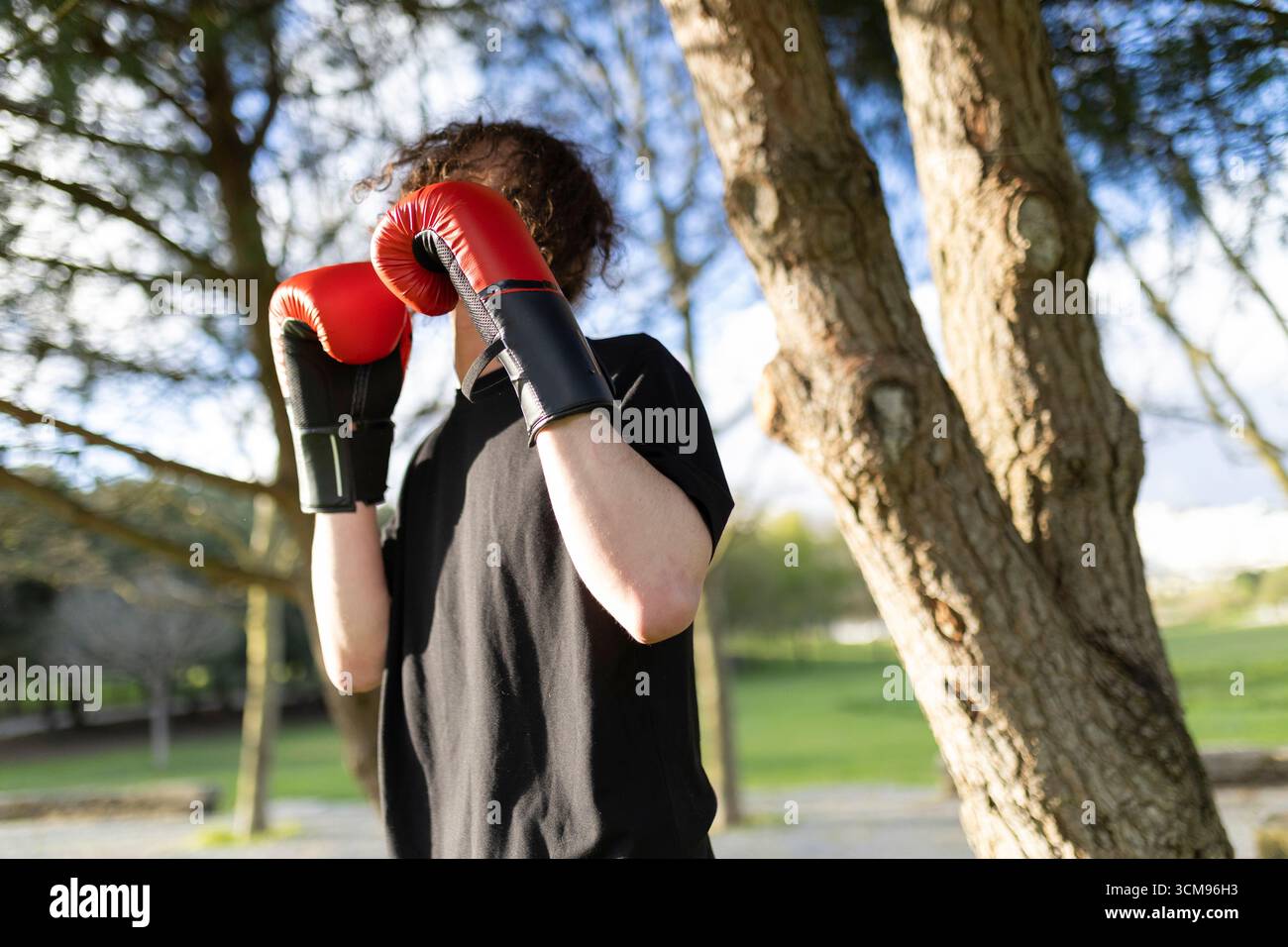 Young man wearing boxing gloves practicing in park Stock Photo