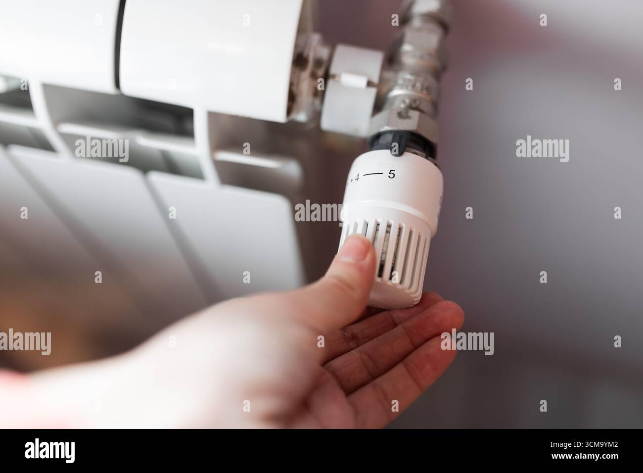 Hand adjusting radiator thermostat valve set to level five for heating ...