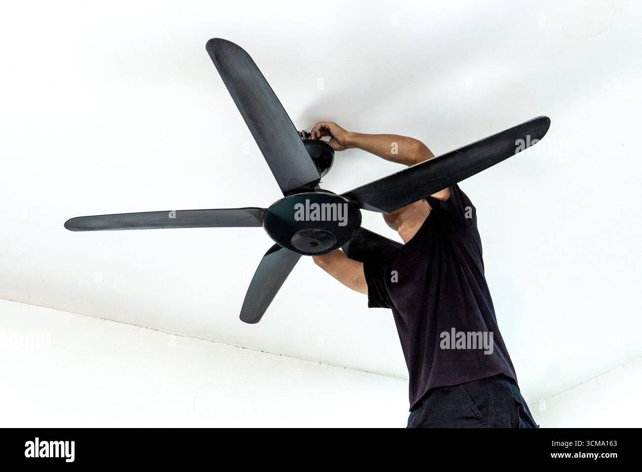 A man installing a ceiling fan. Home improvement, professional work, and technical skill concept. Stock Photo
