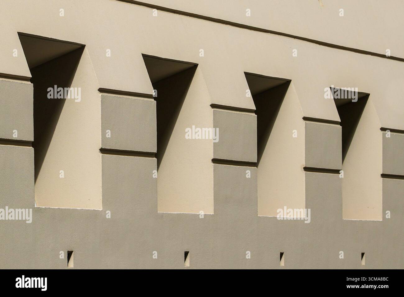 Geometry of Light and Shadow: Aesthetic Vision. The facade of a building in Lyon, France, features angular cutouts that create dynamic patterns of light and shadow. This rhythmic geometry transforms functional elements into an architectural composition that changes throughout the day. Stock Photo