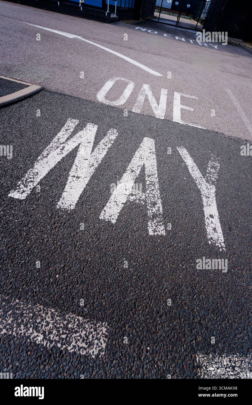 One Way sign and directional arrow, painted in white on a tarmac road Stock Photo