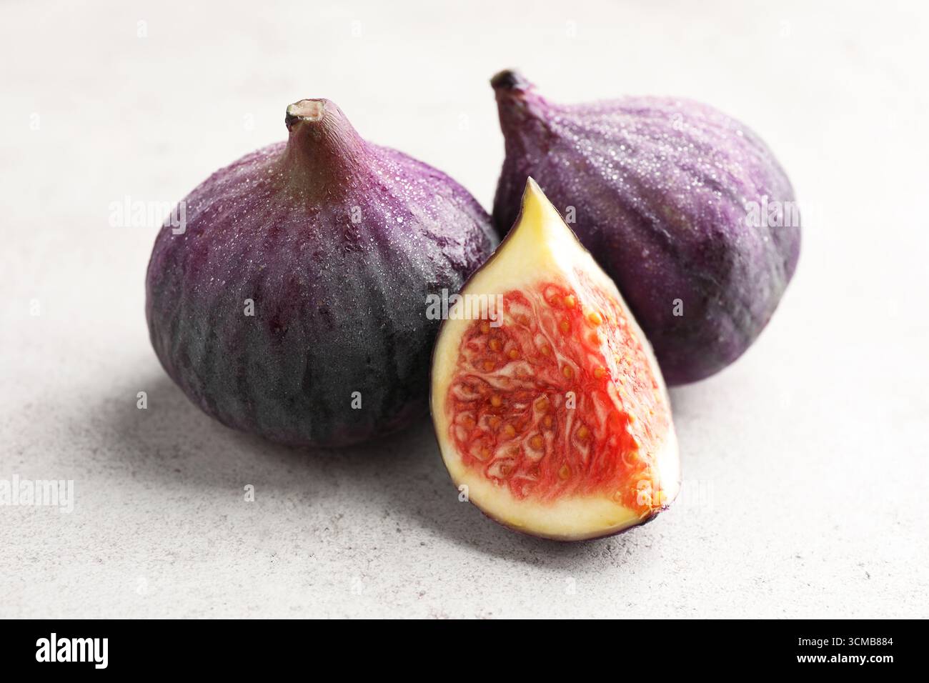 Whole and cut figs on gray textured table, closeup Stock Photo
