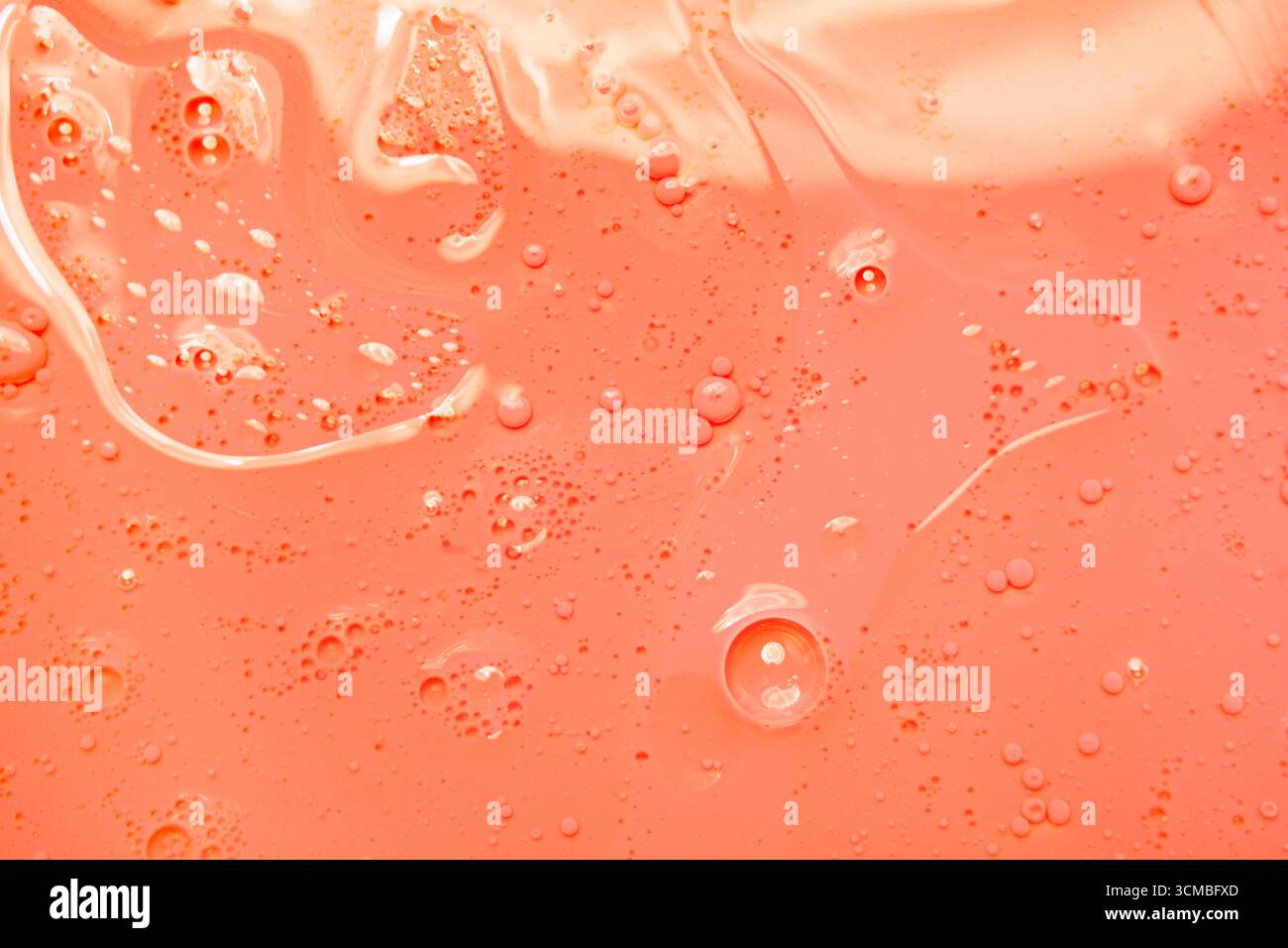 A vibrant orange liquid background showcasing delicate bubbles and swirling patterns, creating a dynamic and abstract visual effect. Ideal for creativ Stock Photo