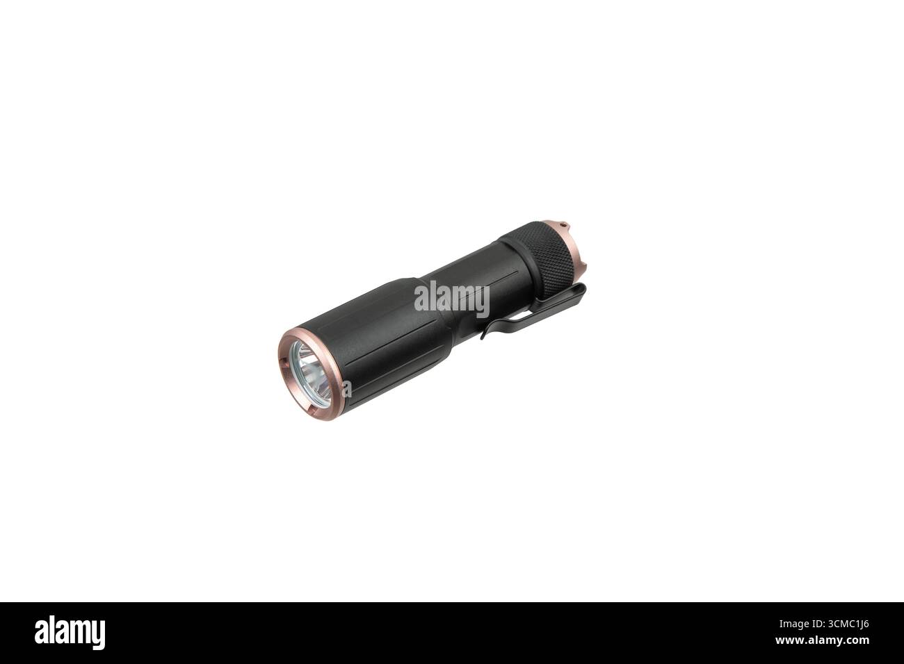 A compact black and copper-colored LED flashlight, isolated on a white background. Stock Photo