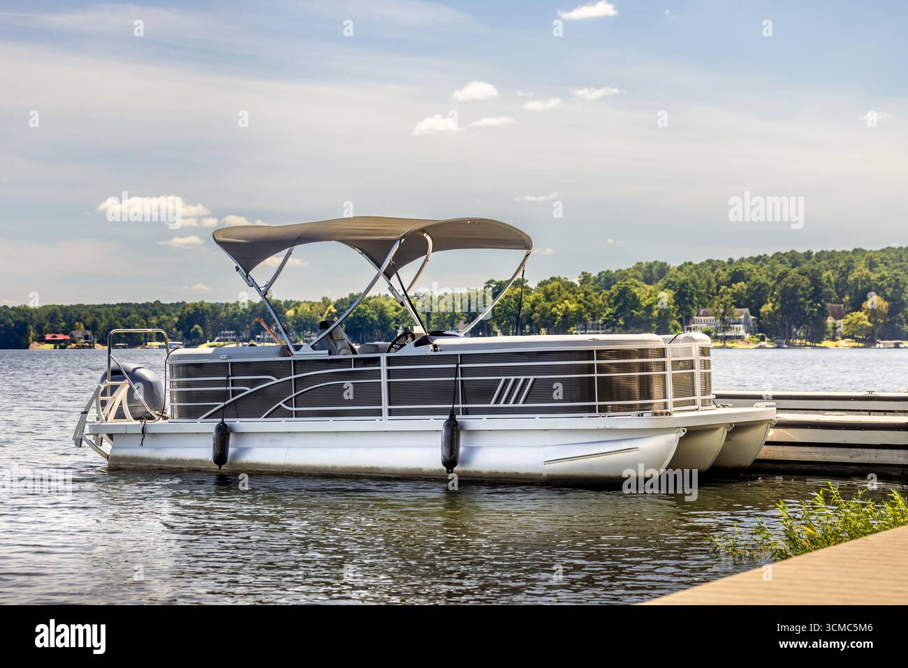 Pontoon boat at private marina dock on freshwater lake. Stock Photo
