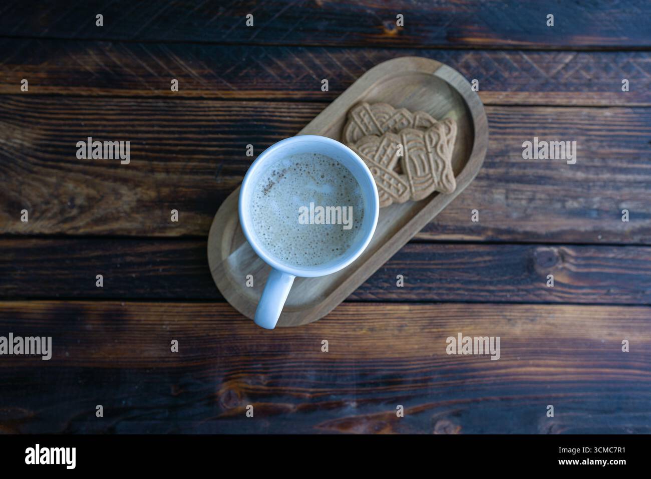 Hot cappuccino served with cookies on a wooden tray. A cozy coffee break on rustic wood background. Stock Photo