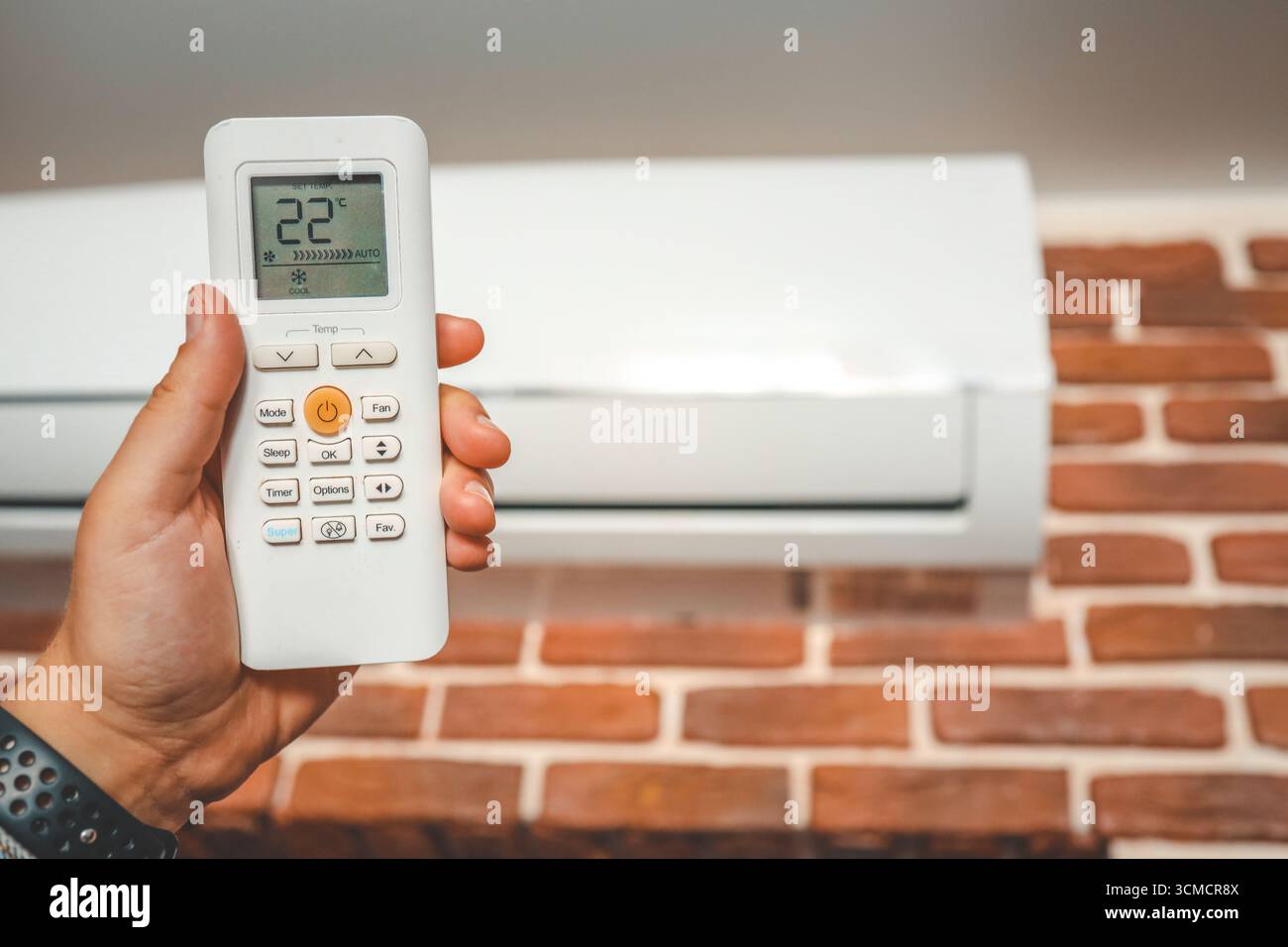 Hand with remote control directed on the conditioner. Stock Photo