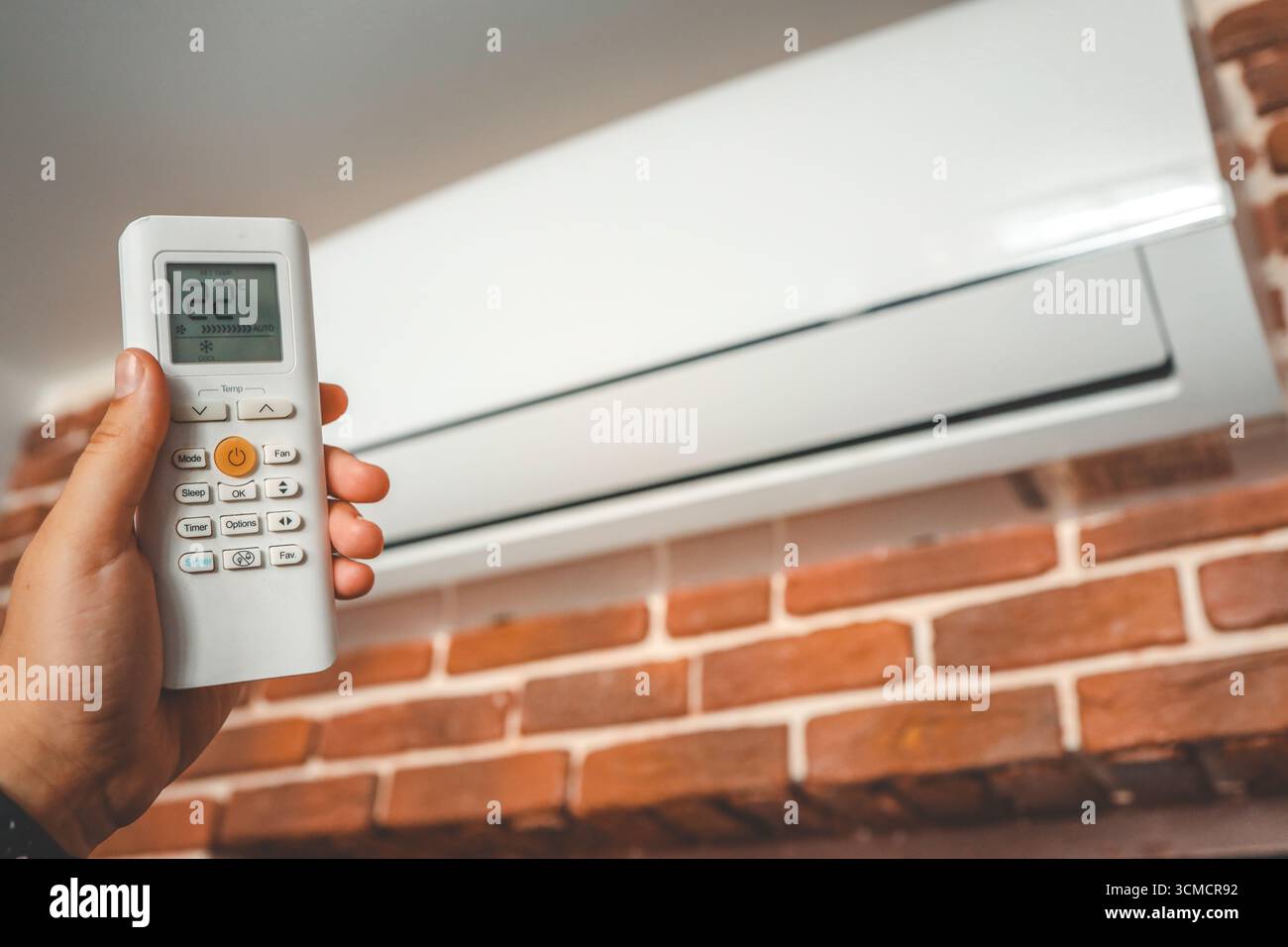 Hand with remote control directed on the conditioner. Stock Photo