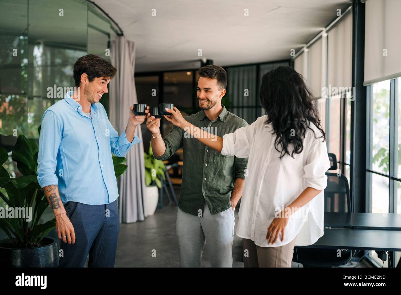 Happy creative diverse colleagues having fun while talking and drinking coffee, tea in working break Stock Photo