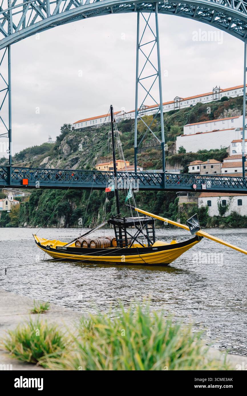 Traditional Portuguese rabelo boat navigates Douro River beneath iconic ...