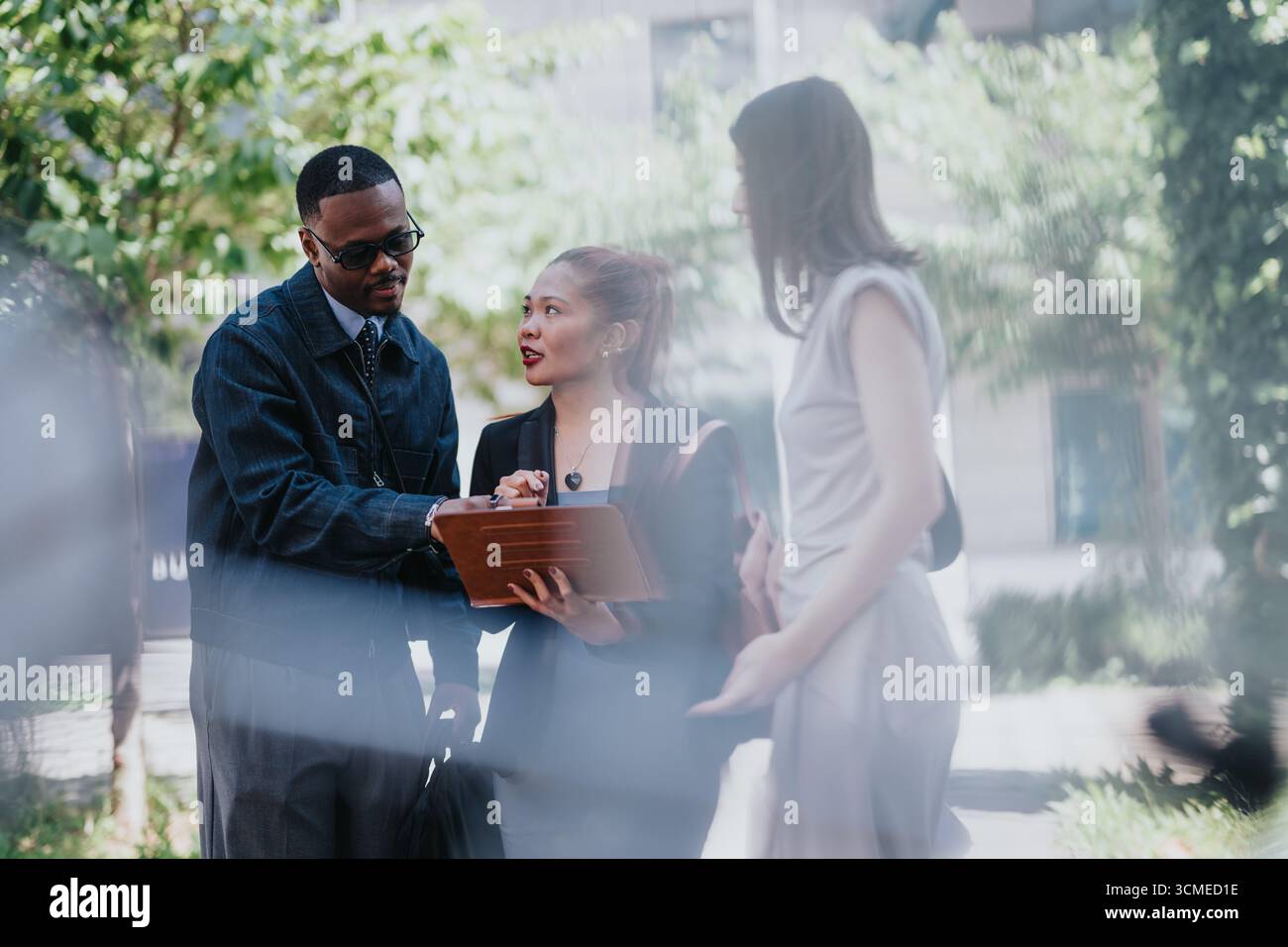 Diverse colleagues collaborating outdoors on a project featuring a digital tablet Stock Photo