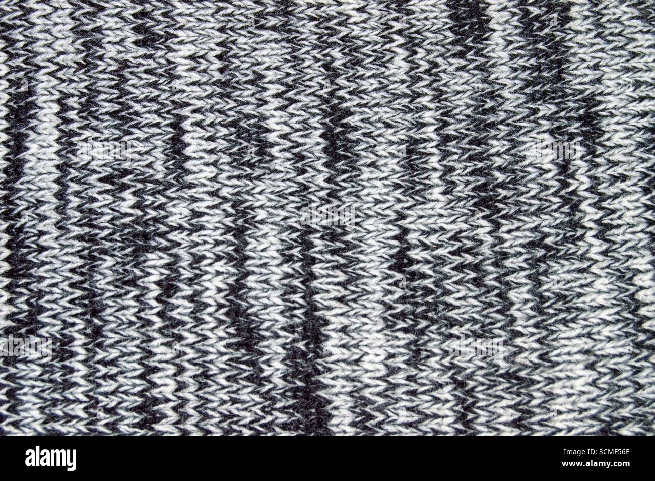 Close-up texture of a grey and white knitted wool fabric background. Seamless macro view of marled knit pattern material for sweater, clothing, and te Stock Photo