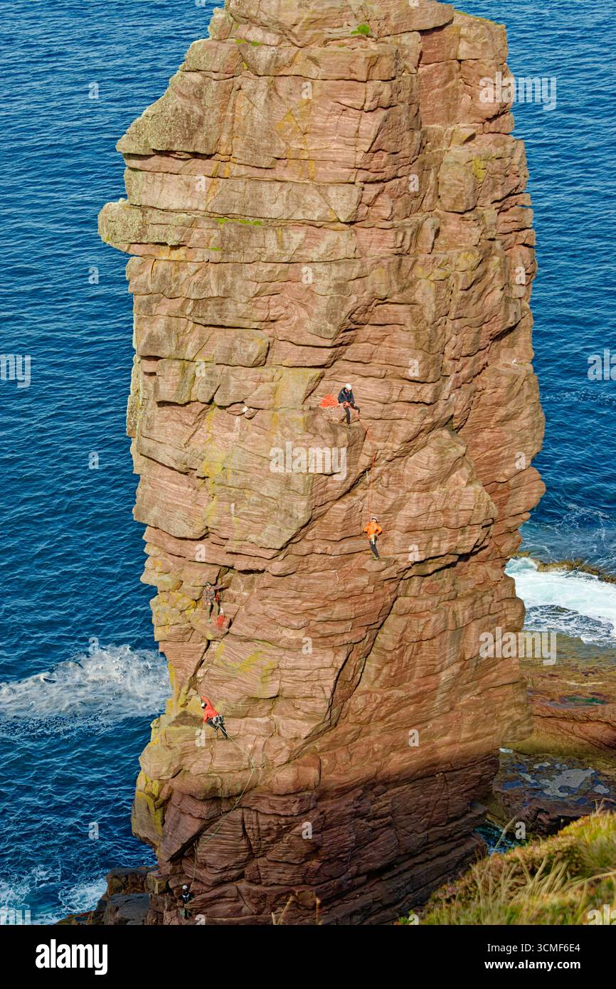 Old Man of Stoer in Sutherland Scotland the 200 ft or 60 meter Torridonian sandstone sea stack with intrepid climbers Stock Photo