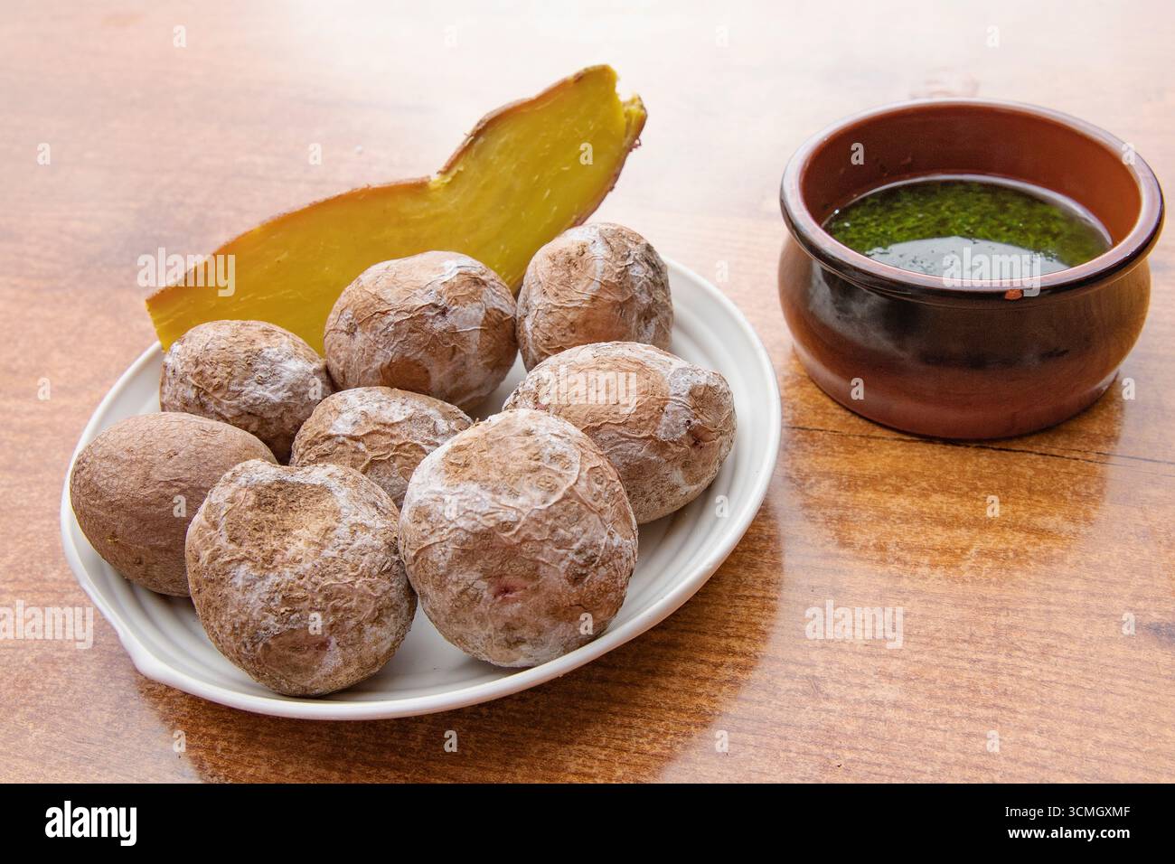 Traditional Canarian wrinkled potatoes papas arrugadas served with green mojo sauce and pumpkin slice. Typical Canary Islands cuisine concept, Spanish Stock Photo