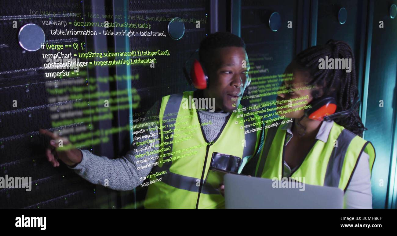 Technicians wearing safety vests pointing at server rack using laptop in data center, code overlay Stock Photo