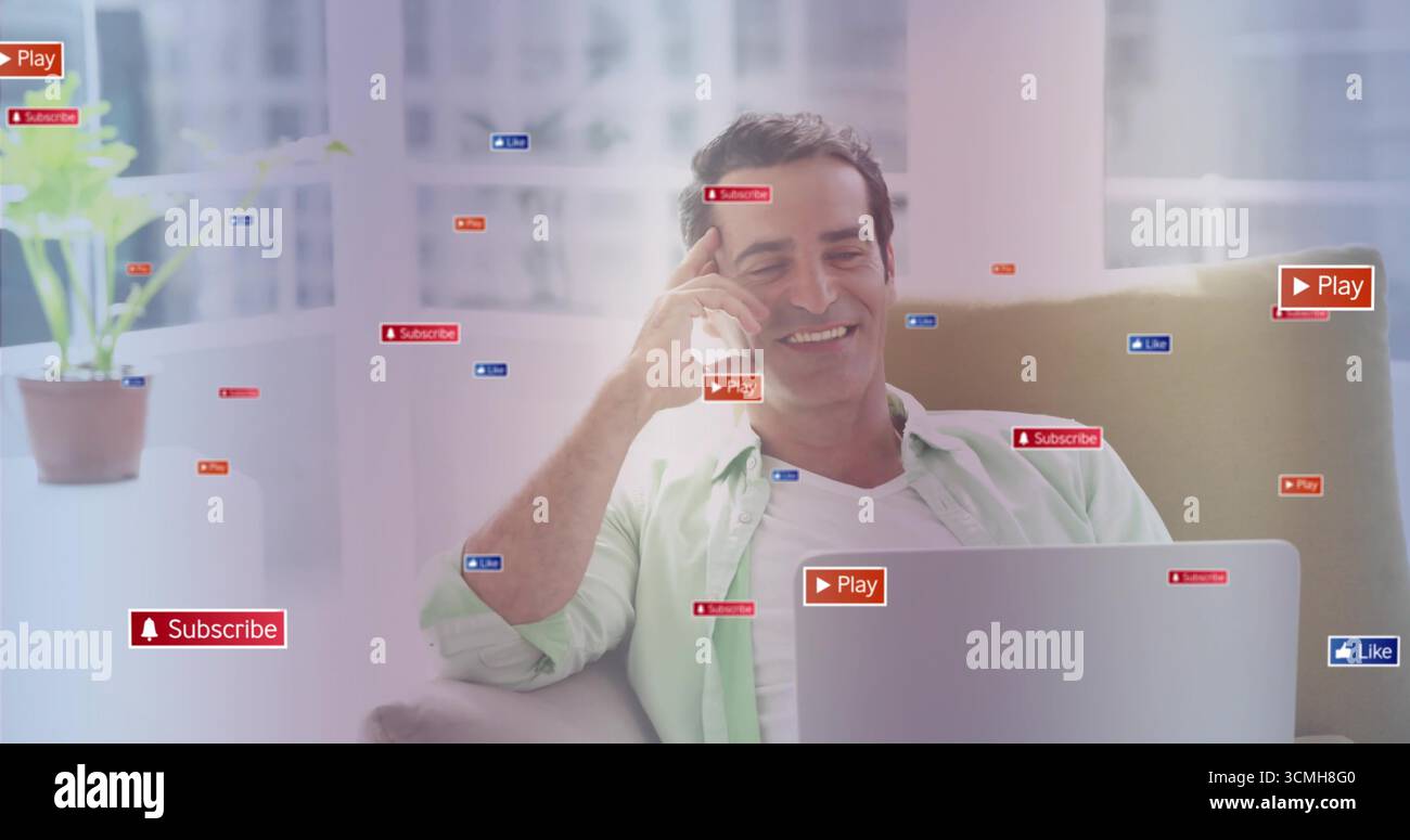 Smiling man using smartphone, laptop on sofa at home, with social media icons and potted plant Stock Photo