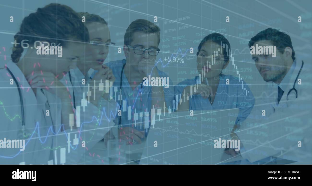 Reviewing medical team in scrubs analyzing charts on laptop in meeting room, candlestick graphs Stock Photo